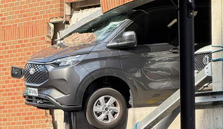 Pedestrians rushed to hospital after being hit by falling rubble when van ploughed through wall and was left dangling from car park building