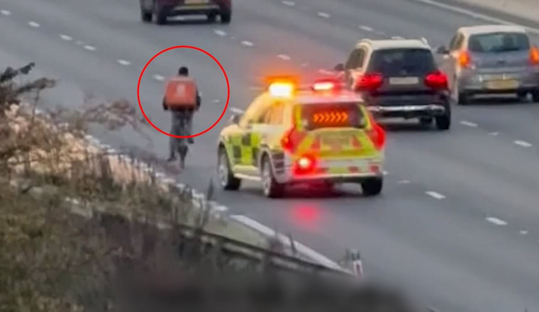 Moment delivery rider pedals along the M4 in rush hour traffic before officers pull him over