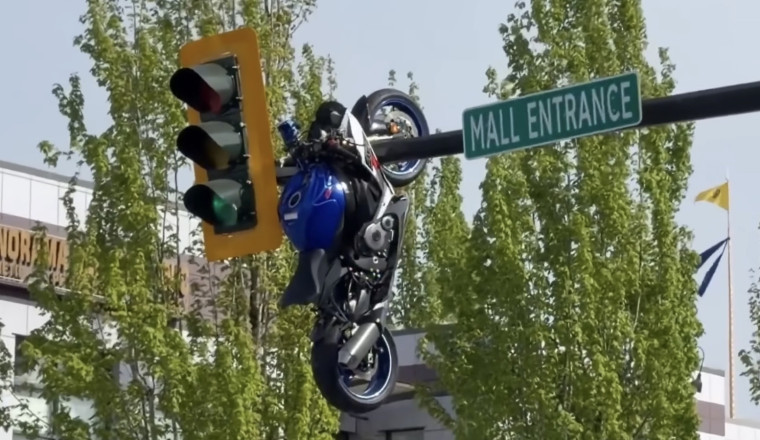 A Motorcycle Hit a Car. The Car Stayed on the Road. The Motorcycle Ended Up Hanging From the Traffic Light.